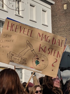 A sign that says "Stop climate crime" with a drawing of a pile of money stabbing the Earth with a knife